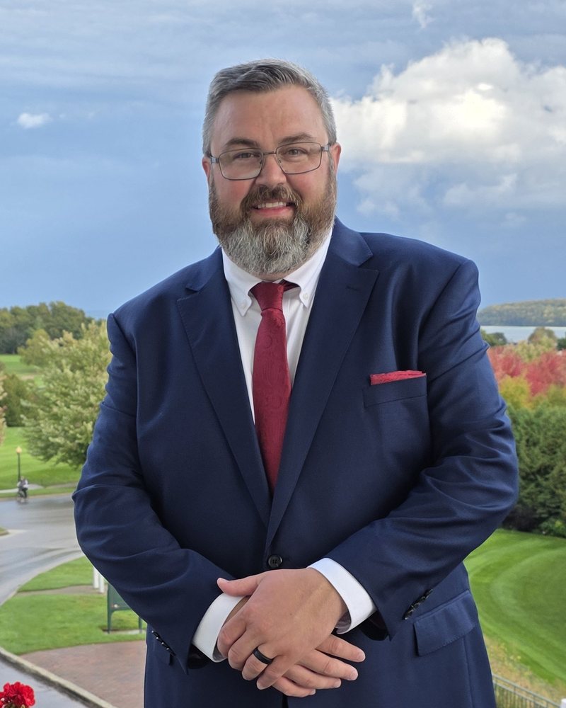 Portrait of Ken Kehler in a navy suit on an outdoor balcony